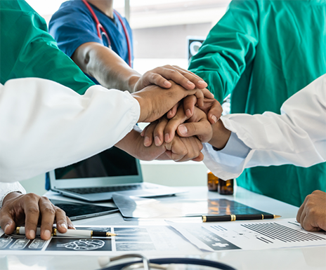 Group of doctors in a circle placing their hands together in the middle