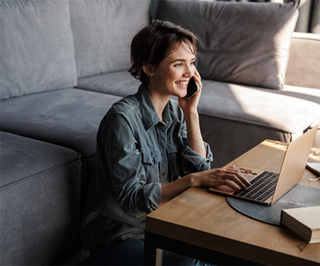 Woman smiling while talking on the phone and using a laptop