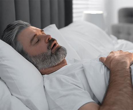 Older man sleeping on his back with his mouth open