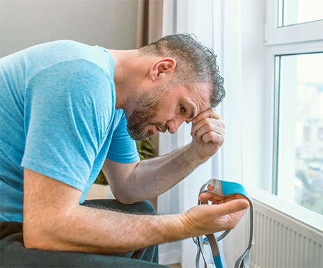 Man rubbing his forehead in frustration and holding a CPAP mask